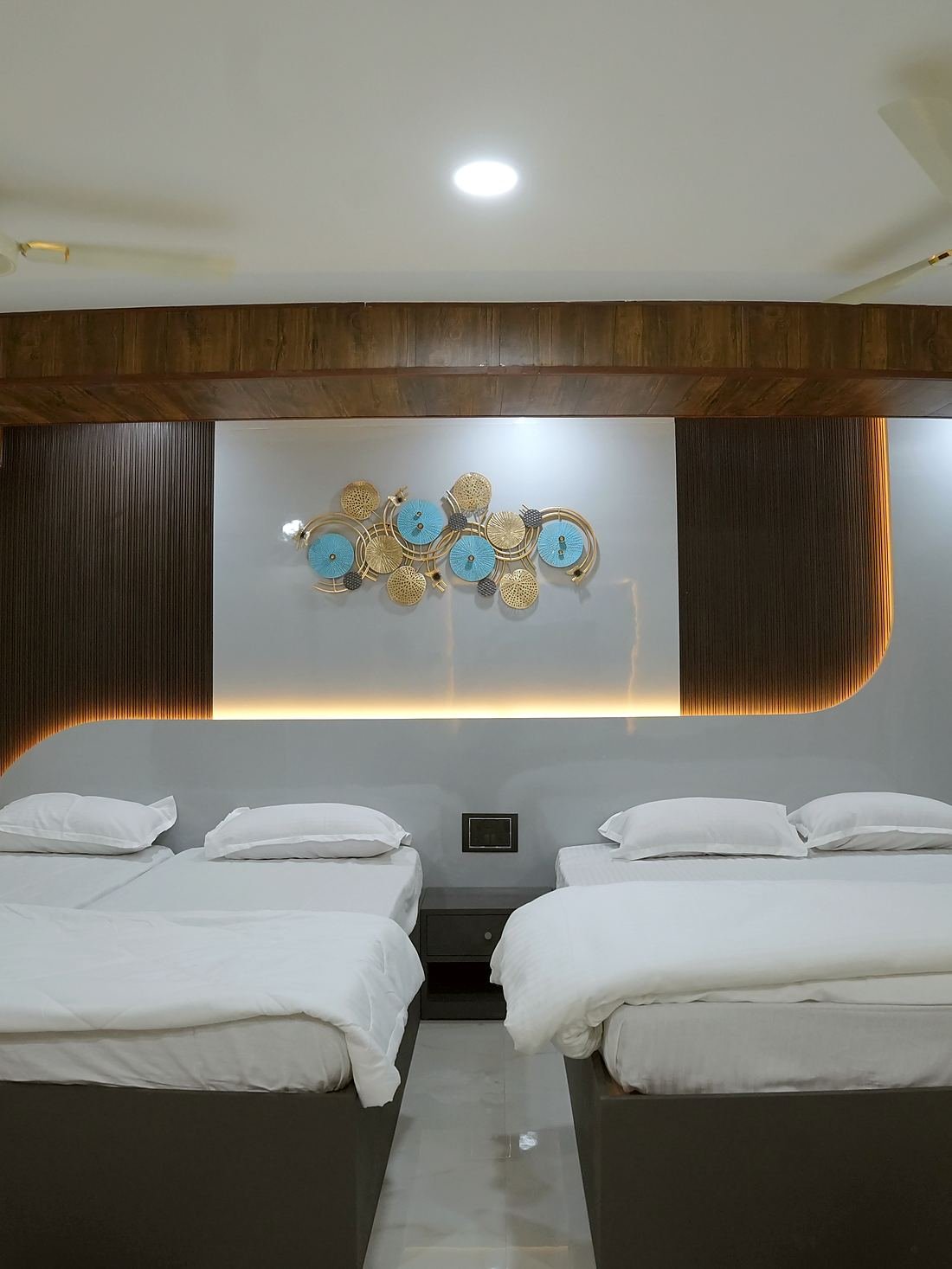 Two beds in the Grand Suite, beneath a curved cove-lit headboard wall