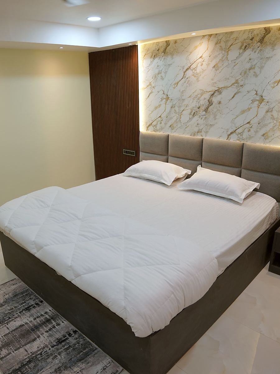 Deluxe Room — king bed beneath a backlit marble feature wall